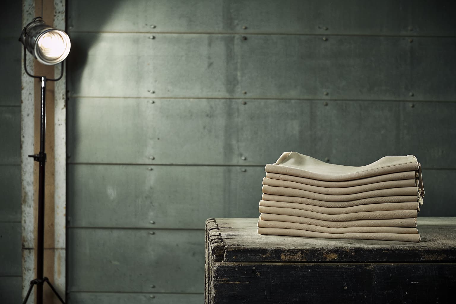 Stack of folded heavyweight tank tops on a dark workbench